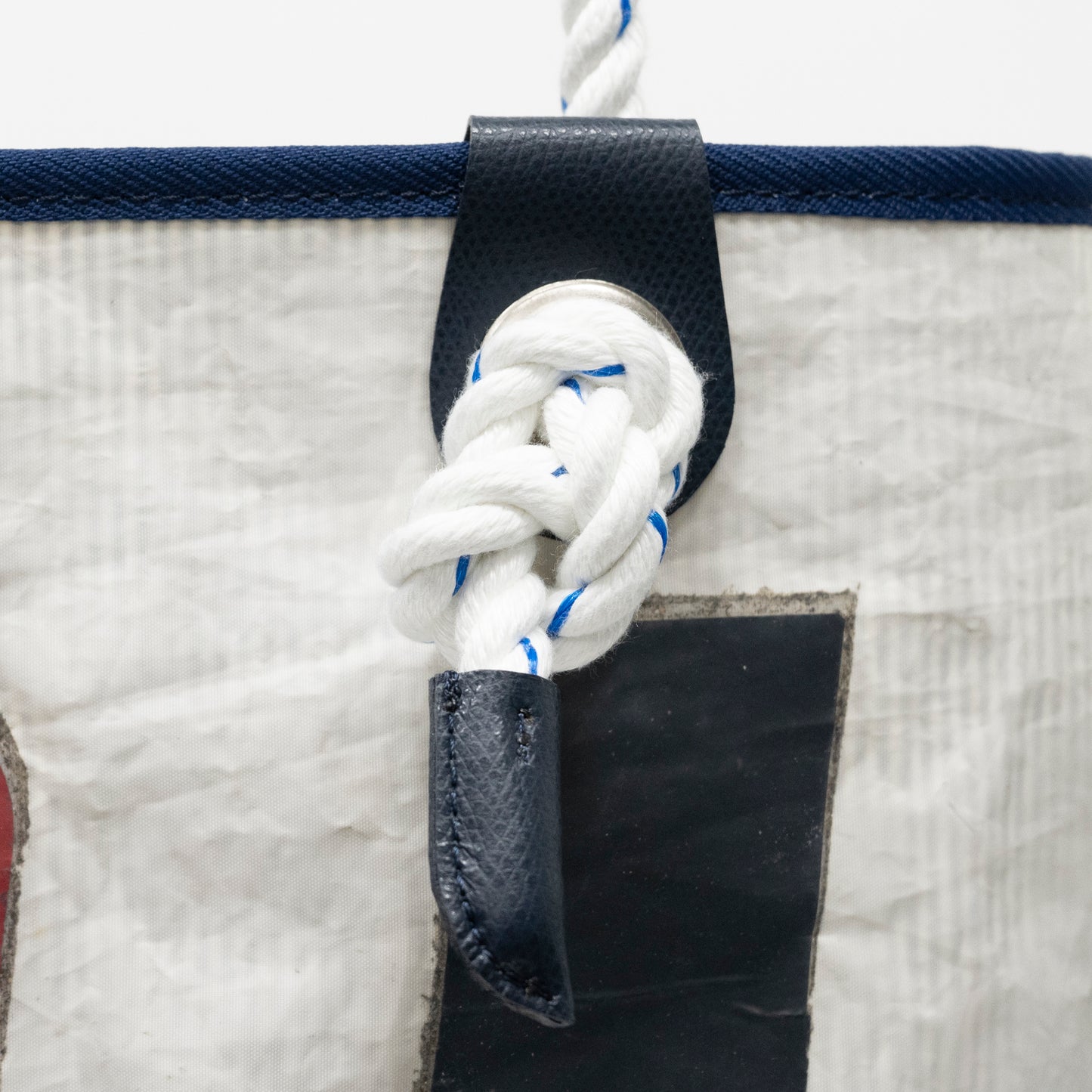 「Marina 横浜・八景島ヨットセイルトートS」のハンドルは、船などでも使われるロープを採用。ホワイトのベースにブルーがきらめく海を感じるデザインです。キュッと結ばれたロープの先が革で留められています。
