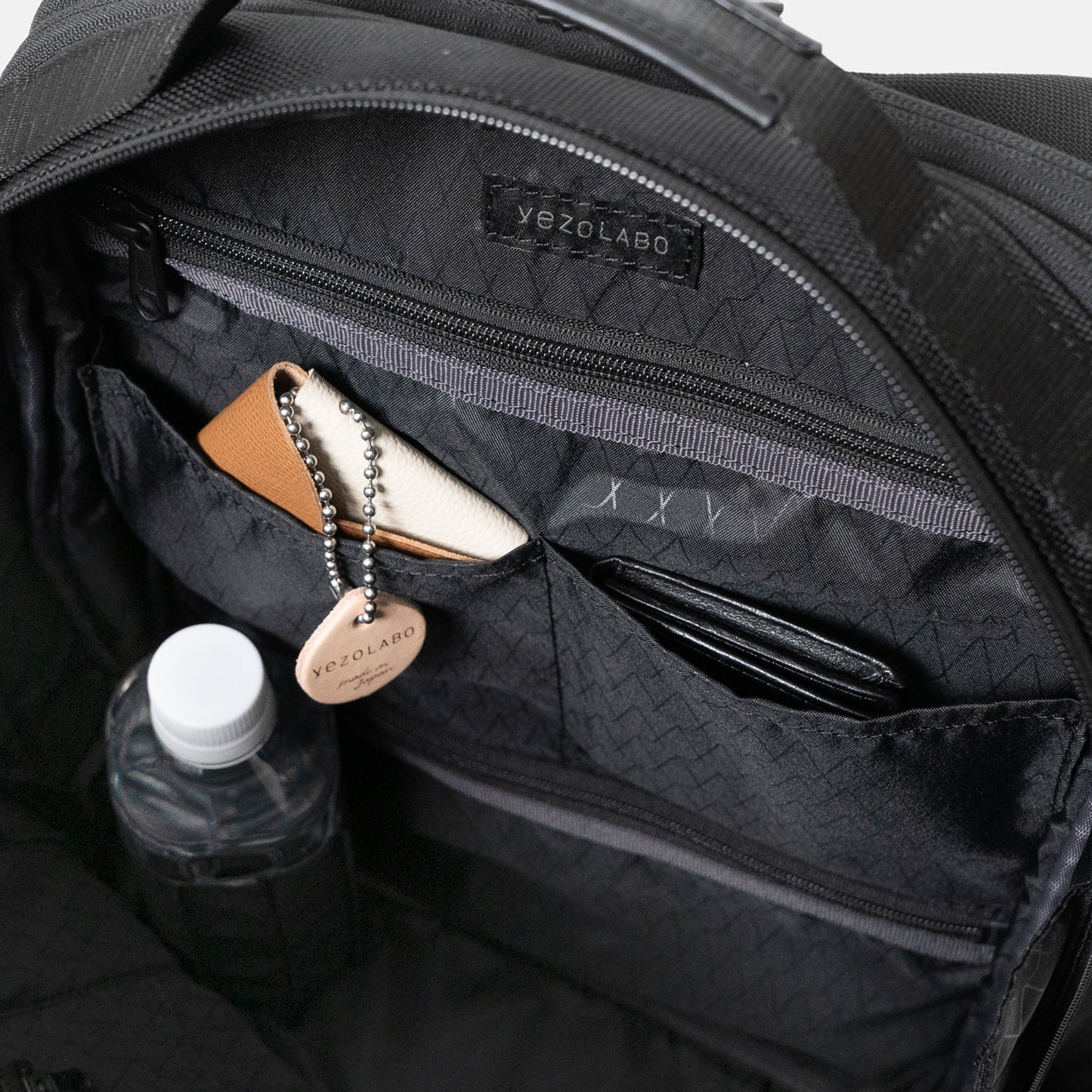 Floe ワーク＆デイリーバックパックの内装にはファスナーポケットを上下に2箇所配置しており、貴重品や散らかりがちな小物などを整理する場所に。中央の仕切りポケットはエコバッグやピルケースなどの小物を収納できます。ペットボトルホルダーには細身の水筒や折り畳み傘などが収納可能。