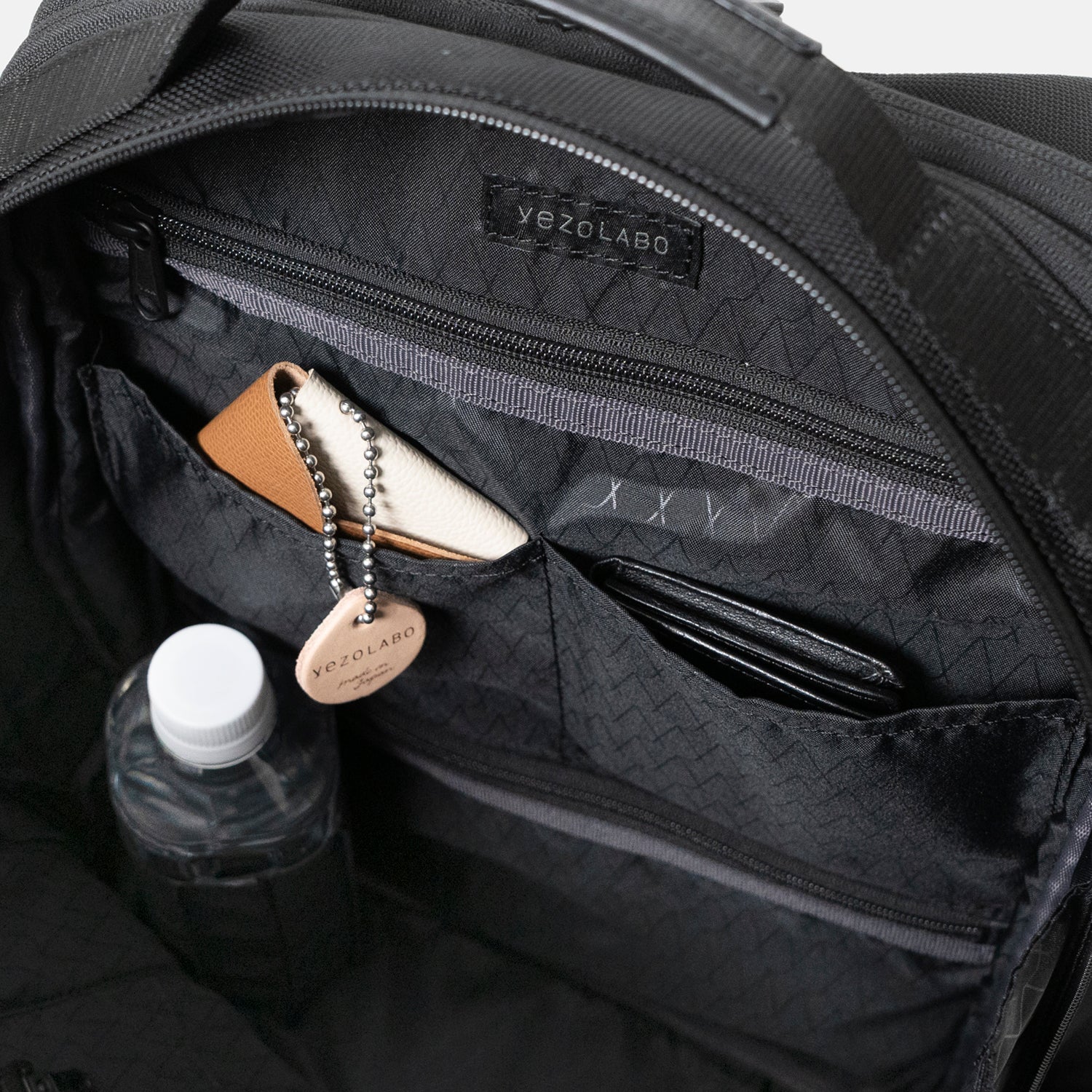 Floe ワーク＆デイリーバックパックの内装にはファスナーポケットを上下に2箇所配置しており、貴重品や散らかりがちな小物などを整理する場所に。中央の仕切りポケットはエコバッグやピルケースなどの小物を収納できます。ペットボトルホルダーには細身の水筒や折り畳み傘などが収納可能。