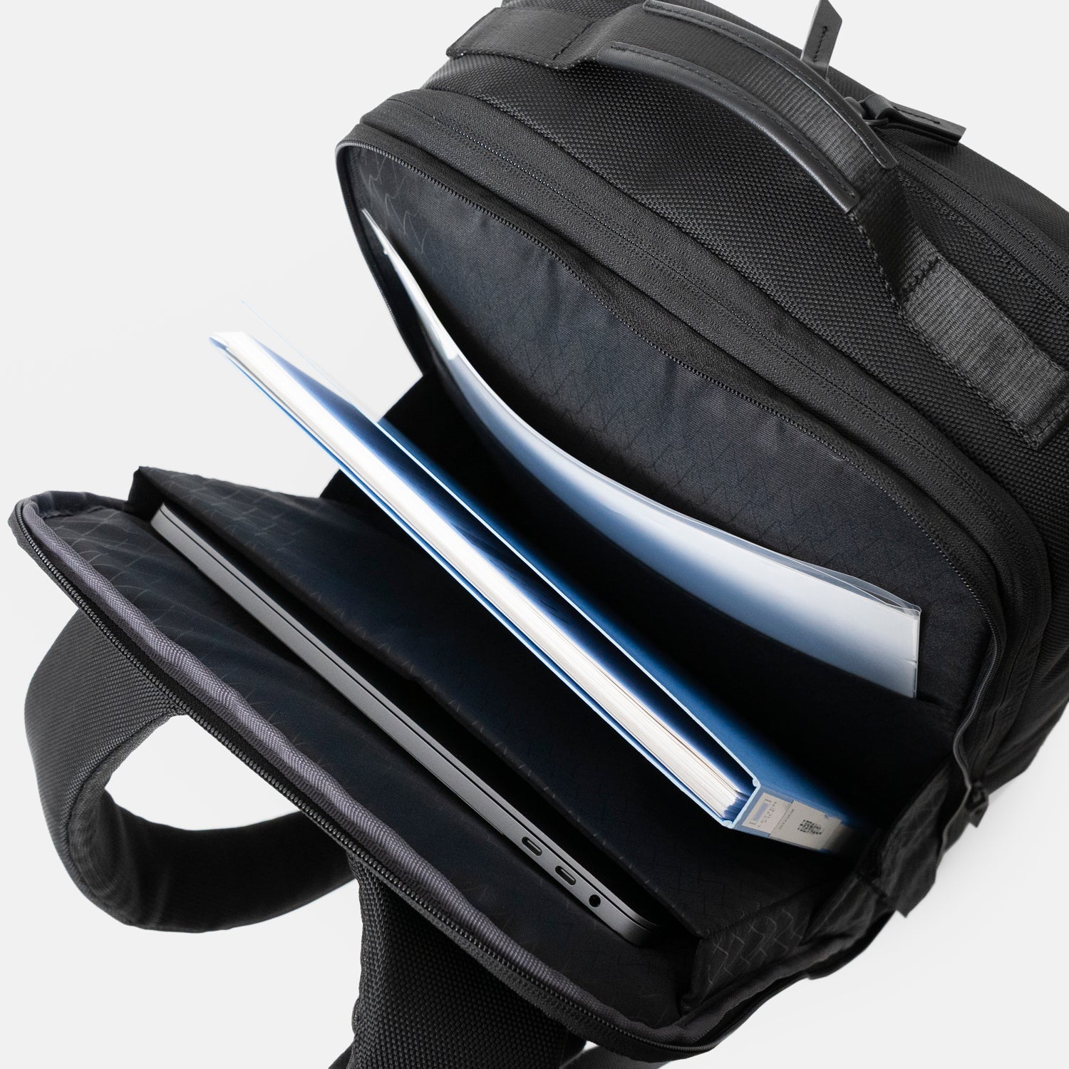 Floe ワーク＆デイリーバックパックLは下まで大きく開くため、荷物の出し入れをスムーズに行えます。背面側のクッション入り仕切り部分には15.6インチノートPC、反対側の仕切りポケットにB4クリアファイルなどが収納可能です。左右の下部にササマチがついているので、中央部の空間も荷物を入れる場所としてお使いいただけます。