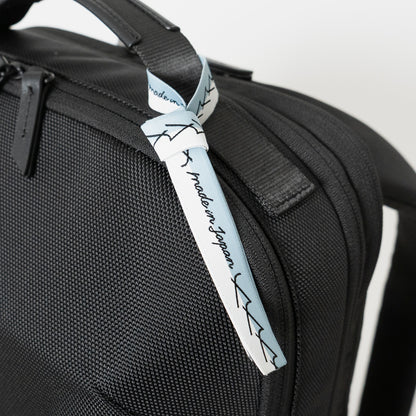 Floe ワーク＆デイリーバックパックはメイドインジャパン・日本製の証が付いています。ブランドマークの”y”を連ねたリボンのデザインで、北海道の空と雪のカラーを取り合わせました。リボンは外してお使いいただくことも可能です。