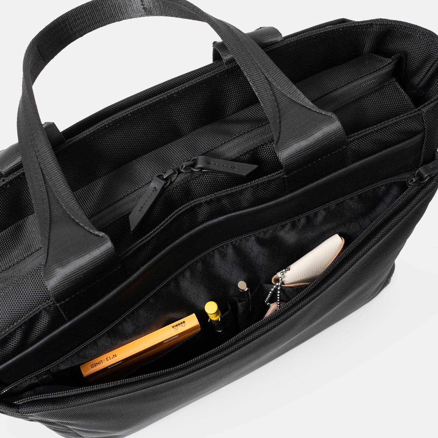 Floe ワーク＆デイリートートバックの前ポケットには、ペンが1本ずつ収納できるペン差し仕切りポケットが2つ、メモ帳や名刺入れなどが入るサイズの仕切りポケットが2つついています。