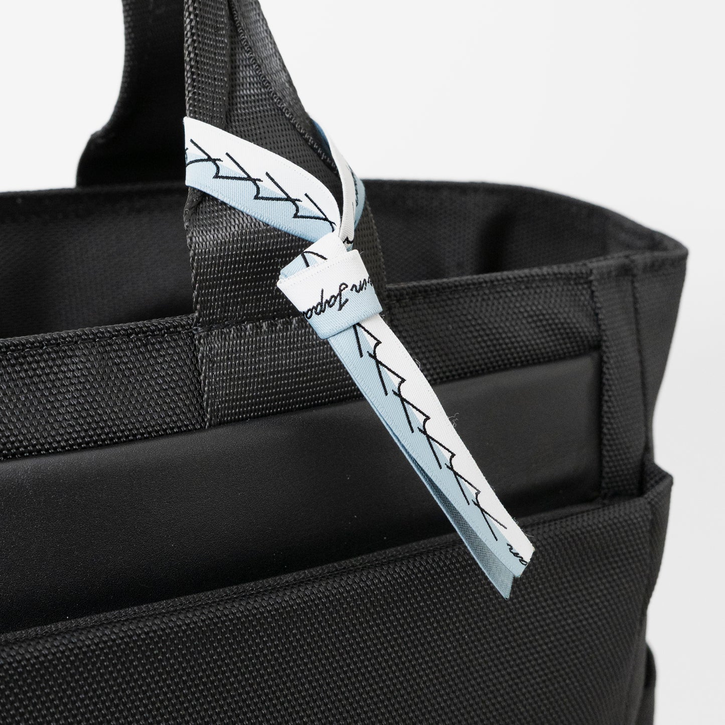 Floe ワーク＆デイリートートバックはメイドインジャパン・日本製の証が付いています。ブランドマークの”y”を連ねたリボンのデザインで、北海道の空と雪のカラーを取り合わせました。リボンは外してお使いいただくことも可能です。